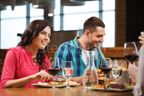 happy couple with friends eating at restaurant Stock photo © dolgachov