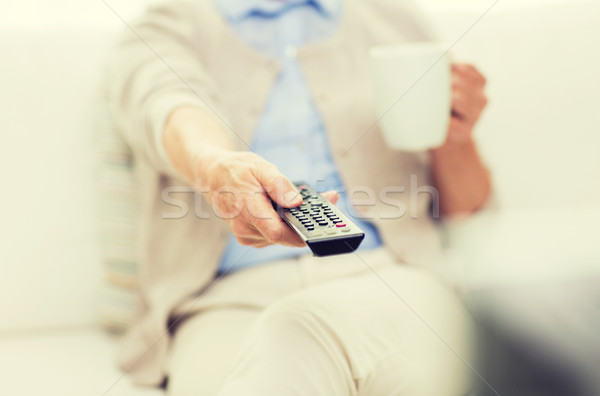 senior woman watching tv and drinking tea at home Stock photo © dolgachov