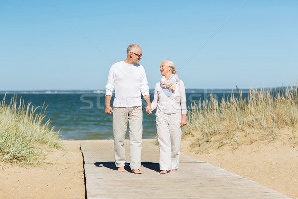 Stock photo: happy senior couple holding hands on summer beach
