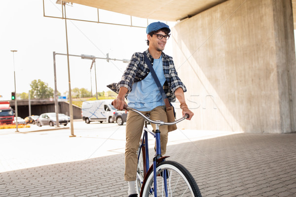 Stock photo: young hipster man with bag riding fixed gear bike