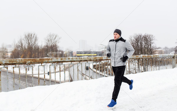 man in earphones running along winter bridge Stock photo © dolgachov