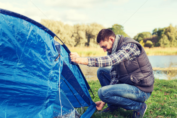 happy man setting up tent outdoors Stock photo © dolgachov