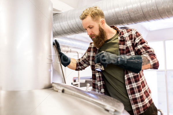 man working at craft brewery or beer plant Stock photo © dolgachov