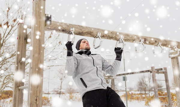 Stock photo: young man exercising on horizontal bar in winter