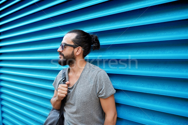 man in sunglasses with bag standing at street wall Stock photo © dolgachov