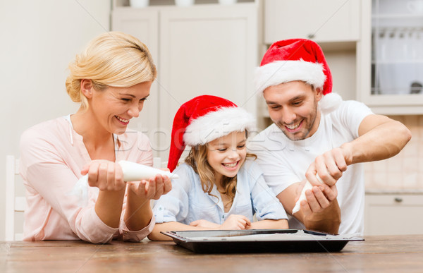 Stock photo: happy family in santa helper hats making cookies