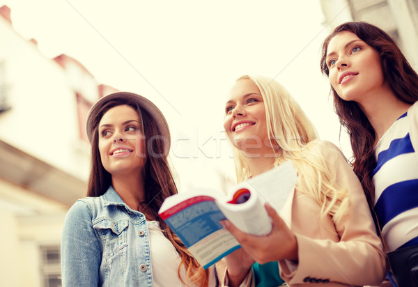three beautiful girls with tourist book in city Stock photo © dolgachov