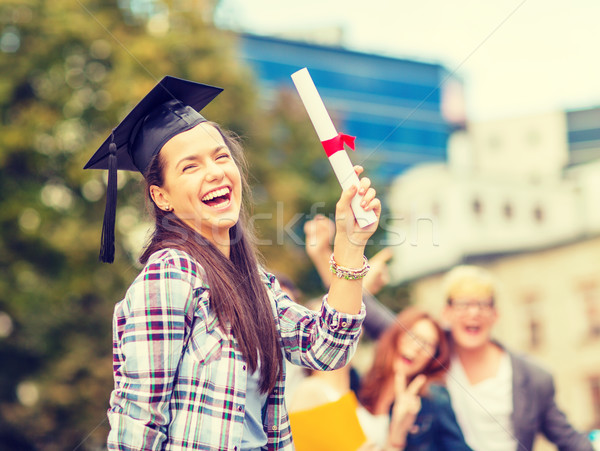 smiling teenage girl in corner-cap with diploma Stock photo © dolgachov