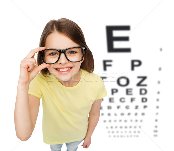smiling little girl in eyeglasses with eye chart Stock photo © dolgachov