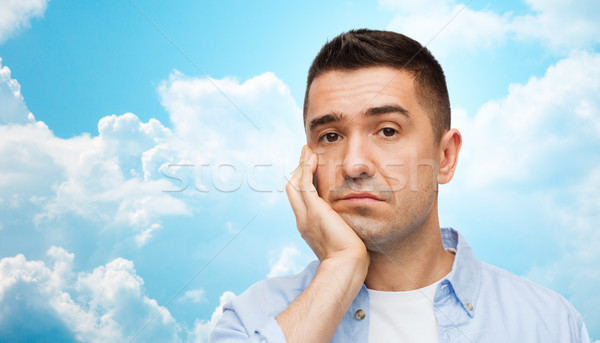 bored man face over blue sky and clouds background Stock photo © dolgachov