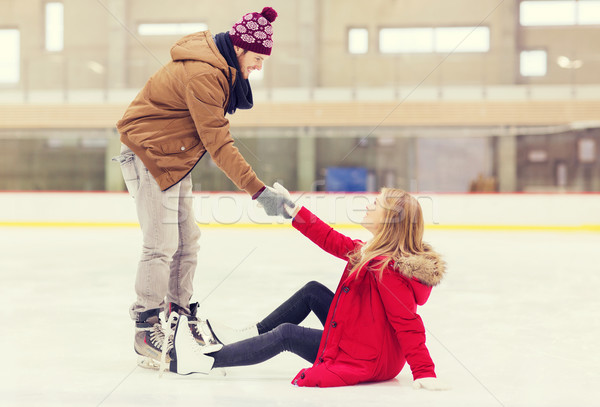 man helping women to rise up on skating rink Stock photo © dolgachov