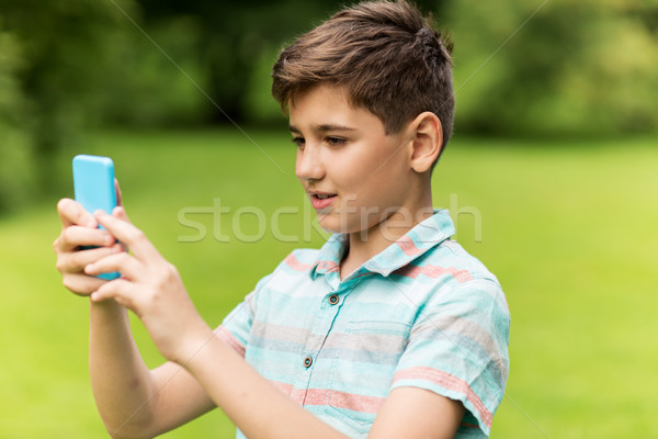 boy with smartphone playing game in summer park Stock photo © dolgachov