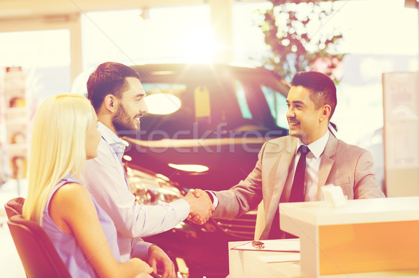 happy couple with car dealer in auto show or salon Stock photo © dolgachov