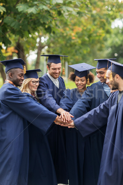 happy students in mortar boards with hands on top Stock photo © dolgachov