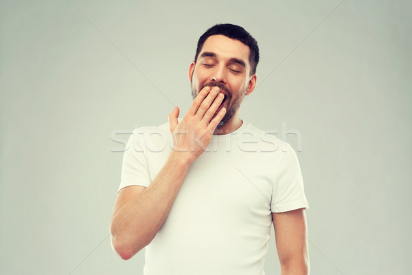 yawning man over gray background Stock photo © dolgachov