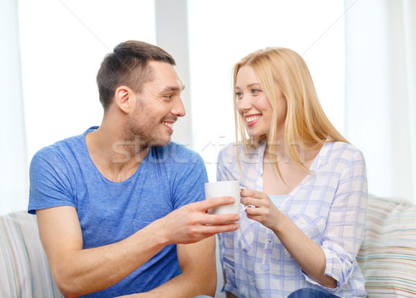 smiling man giving cup of tea or coffee to wife Stock photo © dolgachov
