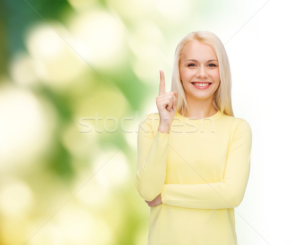 Femme souriante pointant doigt up annonce séduisant [[stock_photo]] © dolgachov
