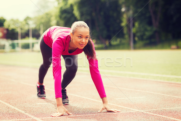 smiling young woman running on track outdoors Stock photo © dolgachov