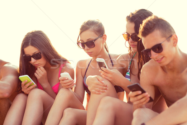 Barátok okostelefonok tengerpart barátság szabadidő nyár Stock fotó © dolgachov