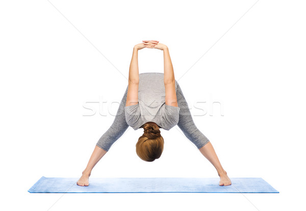 woman making yoga wide-legged forward bend on mat Stock photo © dolgachov