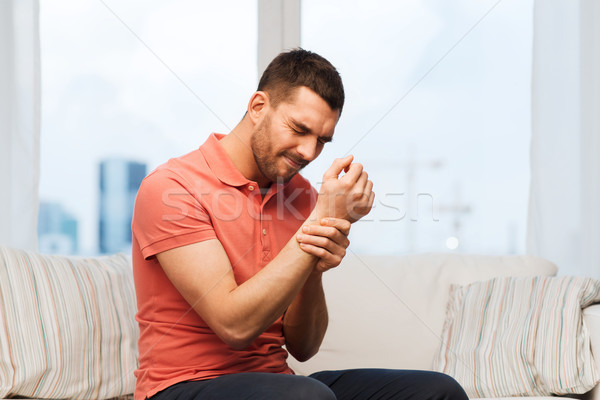 unhappy man suffering from pain in hand at home Stock photo © dolgachov