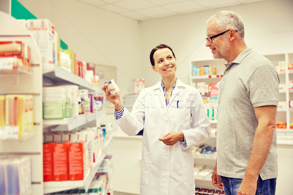 pharmacist showing drug to senior man at pharmacy Stock photo © dolgachov