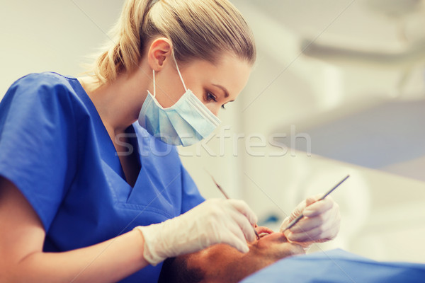 female dentist checking up male patient teeth Stock photo © dolgachov