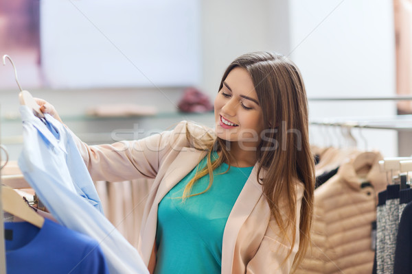 happy young woman choosing clothes in mall Stock photo © dolgachov