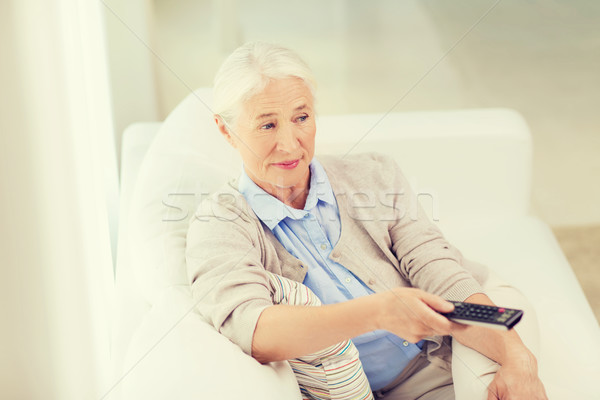senior woman with remote watching tv at home Stock photo © dolgachov