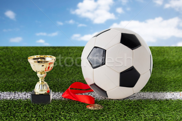 close up of football ball, golden cup and medal Stock photo © dolgachov