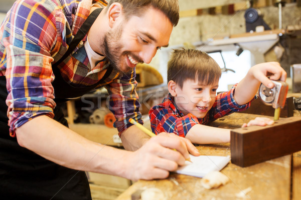 dad and son with ruler measuring plank at workshop Stock photo © dolgachov