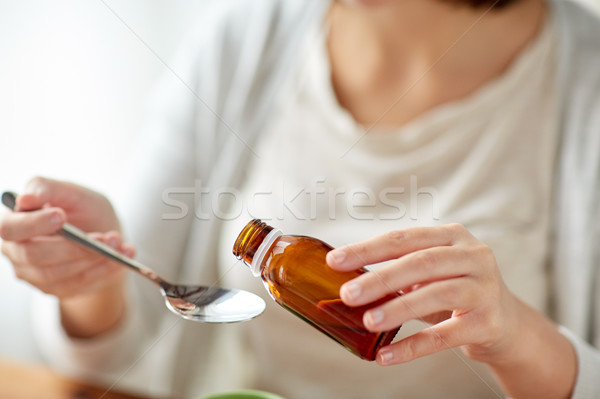 woman pouring medicine from bottle to spoon Stock photo © dolgachov