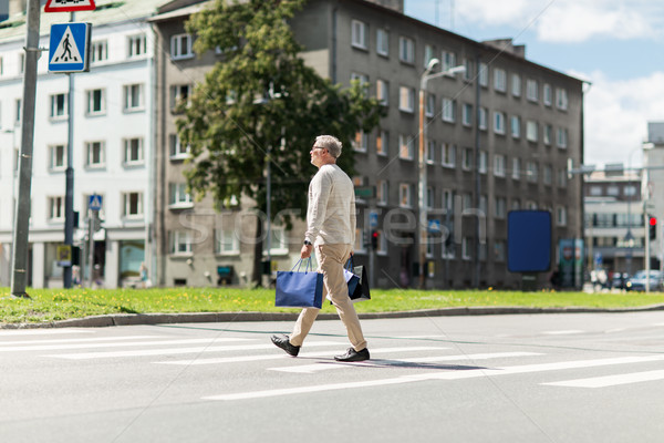 senior man with shopping bags walking on crosswalk Stock photo © dolgachov