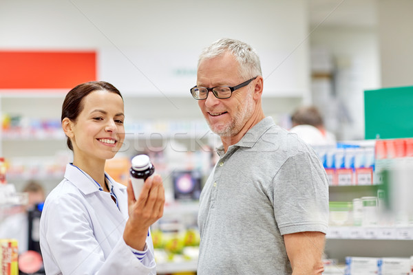 Stock photo: pharmacist showing drug to senior man at pharmacy