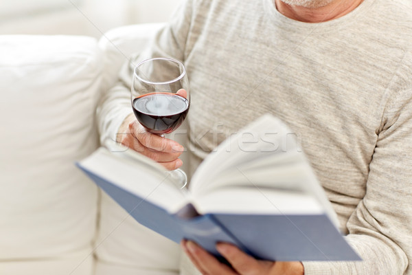 close up of senior man with wine reading book Stock photo © dolgachov