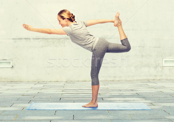woman making yoga in lord of the dance pose on mat Stock photo © dolgachov