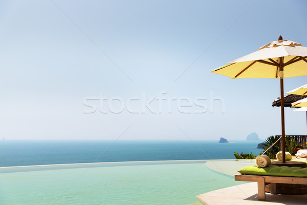 infinity pool with parasol and sun beds at ocean Stock photo © dolgachov