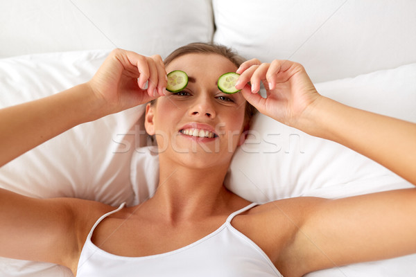 Stock photo: beautiful woman applying cucumbers to eyes at home