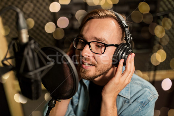man with headphones singing at recording studio Stock photo © dolgachov