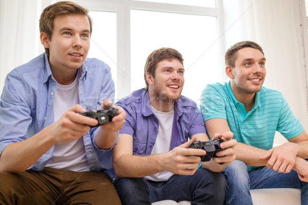 smiling friends playing video games at home Stock photo © dolgachov