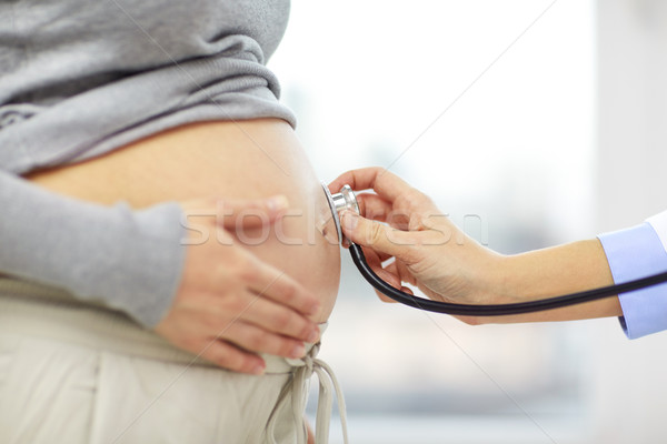 close up of pregnant woman belly and doctor hand Stock photo © dolgachov