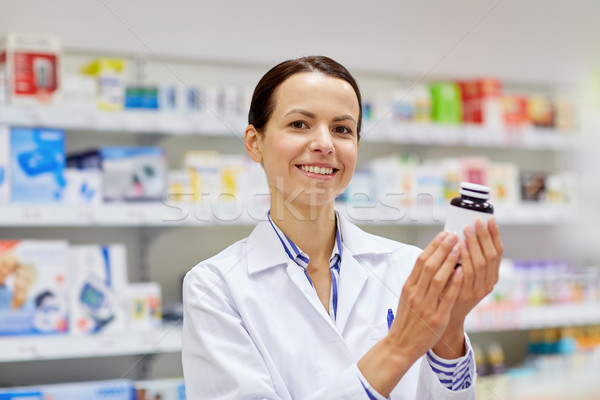 happy female pharmacist with drug jar at pharmacy Stock photo © dolgachov