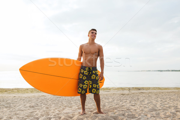 Stock photo: smiling young man with surfboard on beach
