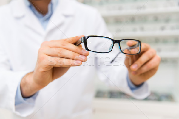 Stock photo: close up of optician with glasses at optics store