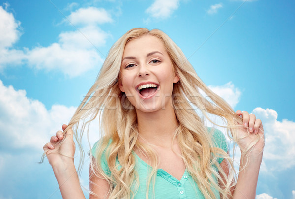 smiling young woman holding her strand of hair Stock photo © dolgachov