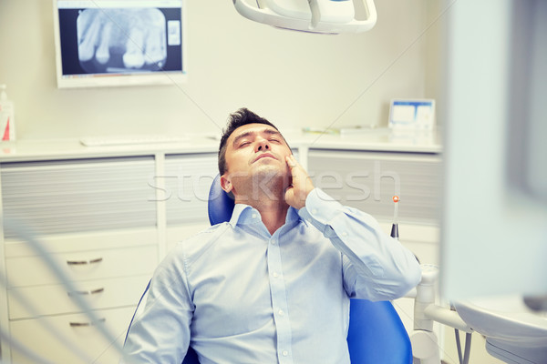 man having toothache and sitting on dental chair Stock photo © dolgachov