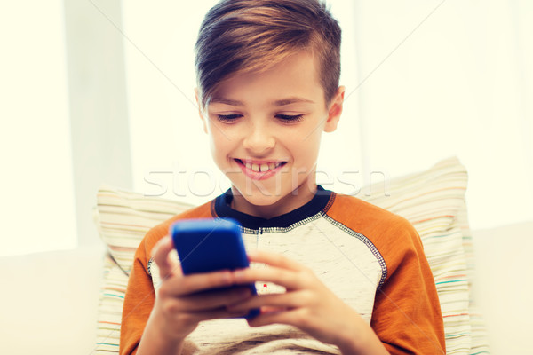 boy with smartphone texting or playing at home Stock photo © dolgachov