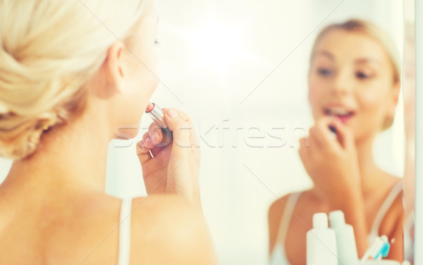 woman with lipstick applying make up at bathroom Stock photo © dolgachov