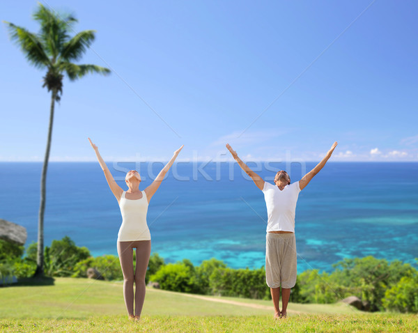 happy couple making yoga exercises on beach Stock photo © dolgachov