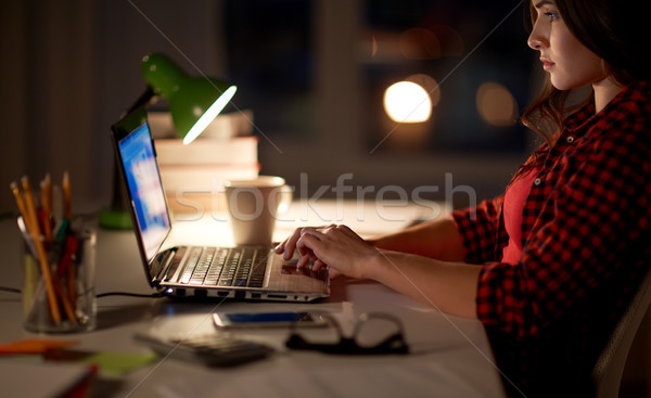 Stock photo: student or woman typing on laptop at night home